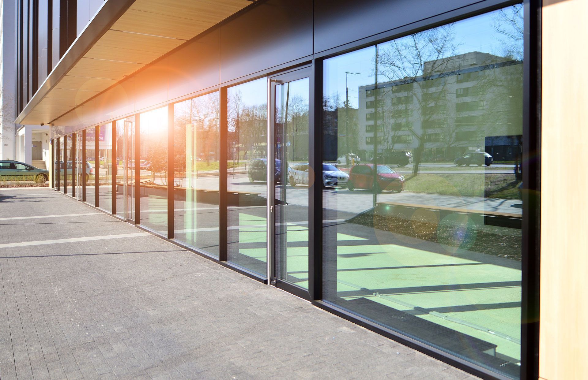 Sunlit storefront with large glass windows and empty sidewalk outside