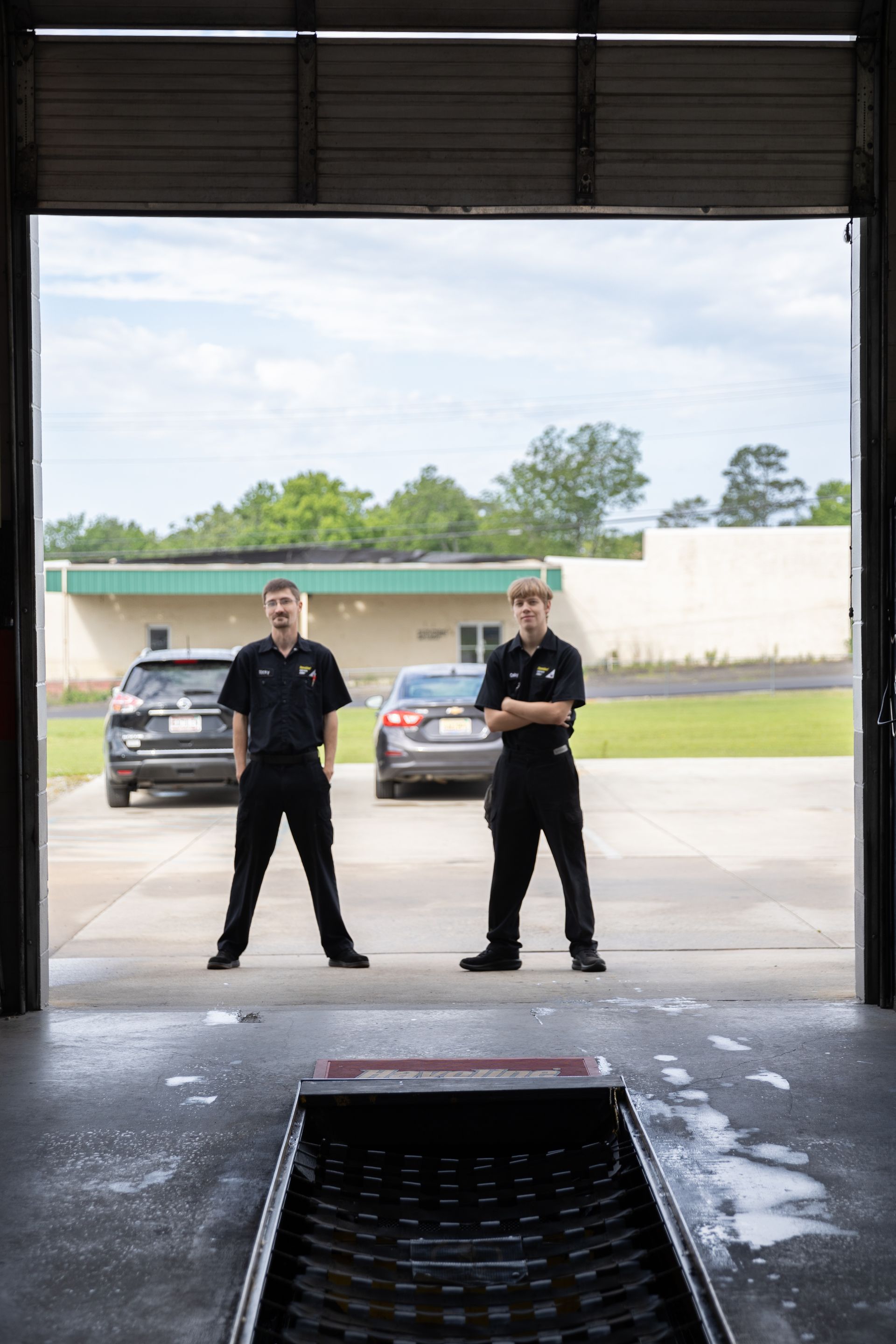 Two men are standing in front of a garage door.