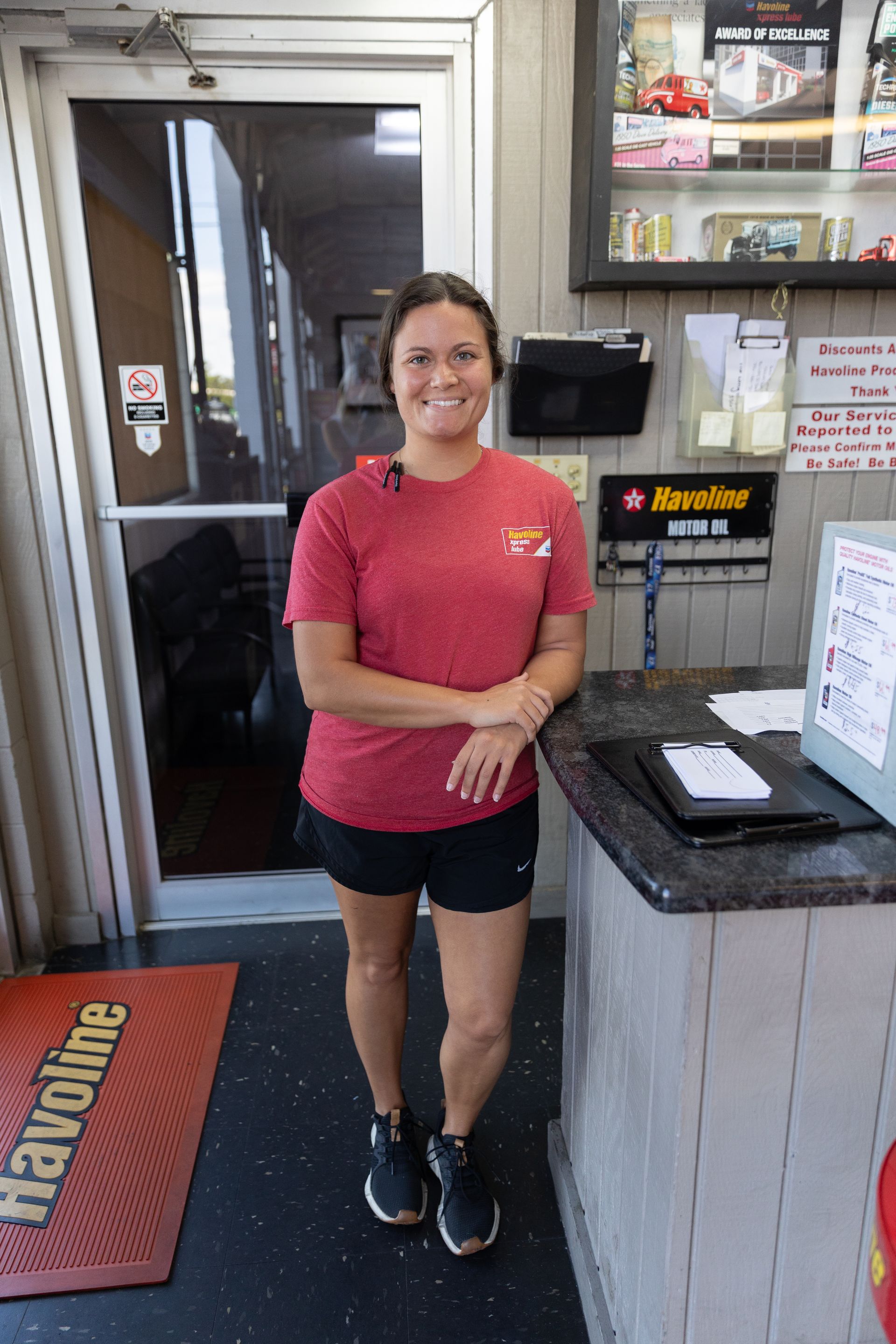 A woman is standing in front of a counter in a gas station.