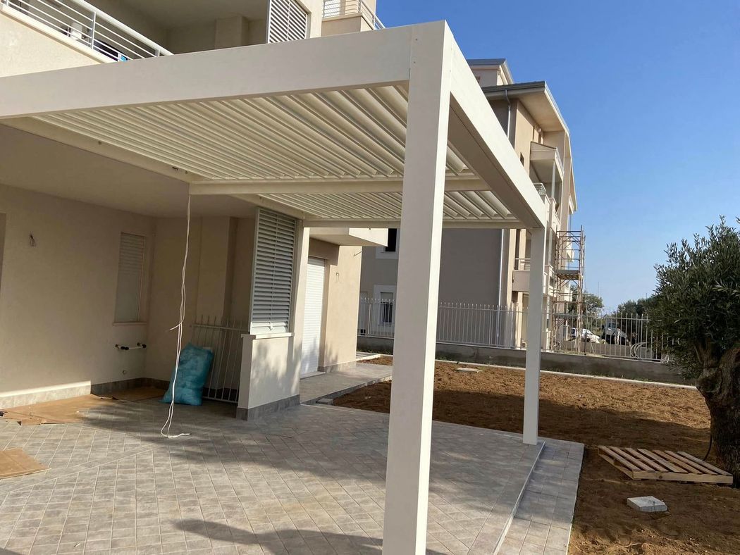 Pergola bioclimatica moderna con lamelle orientabili in un elegante spazio outdoor residenziale.