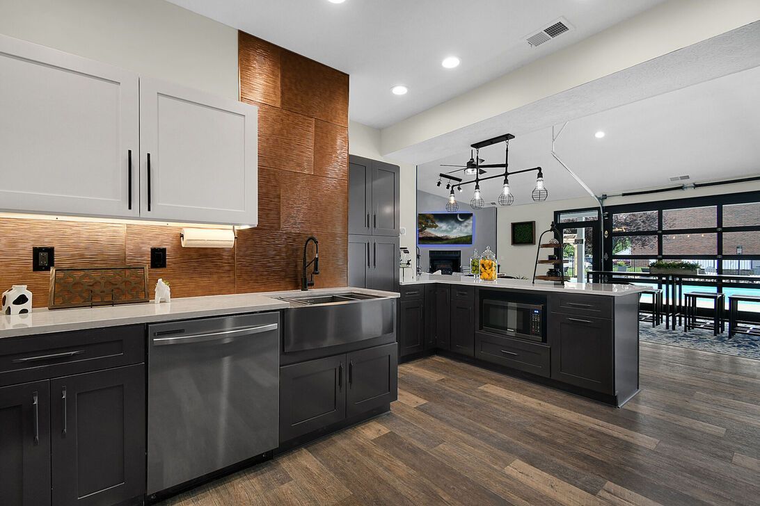 Modern kitchen with black and white cabinets, copper backsplash, and dark wood floors