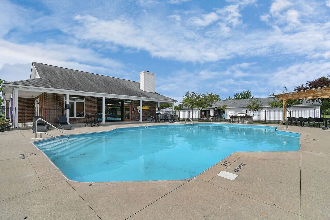 Outdoor swimming pool beside a clubhouse on a partly cloudy day