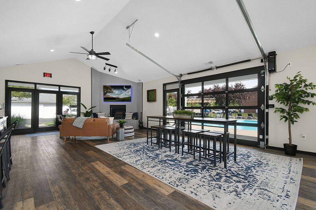 Modern living room with sofa, TV, dining table, large windows, and patterned rug
