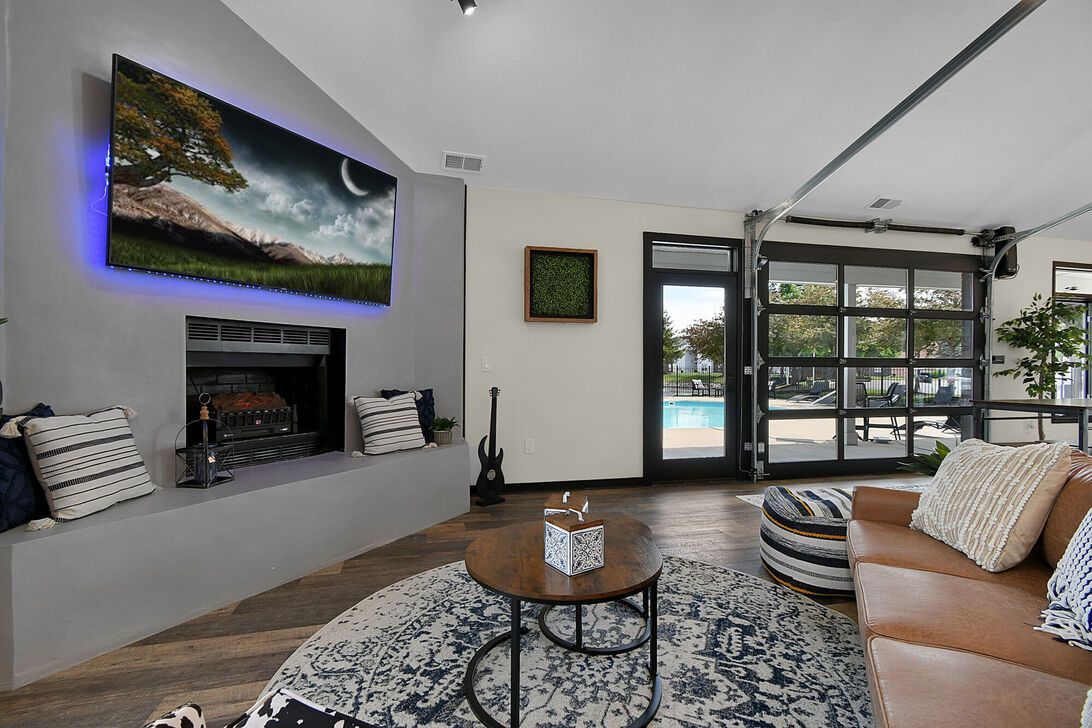 Modern living room with fireplace, large TV, sectional sofa, coffee table, and sliding glass doors.