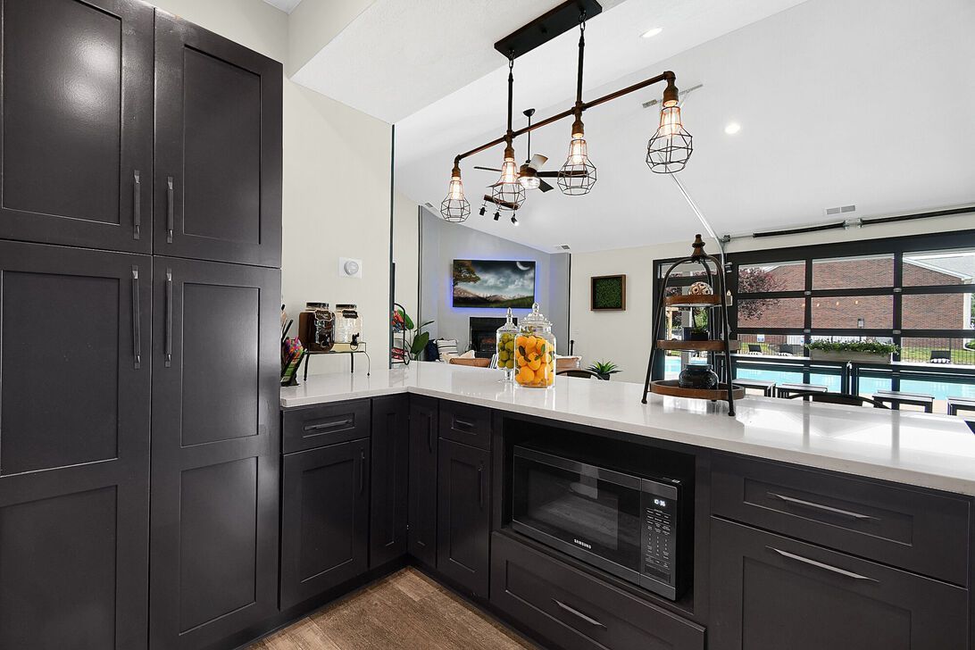 Modern black-and-white kitchen with large island, pendant lights, and window overlooking a patio