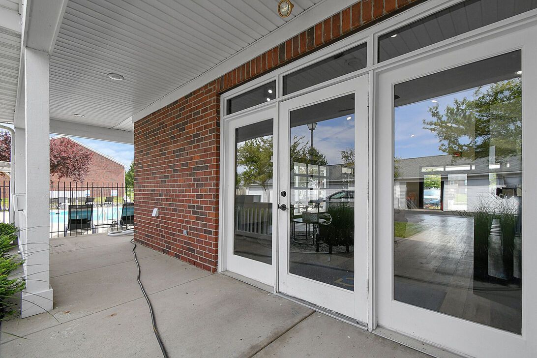 Covered storefront walkway with brick wall, glass doors, and a concrete sidewalk.