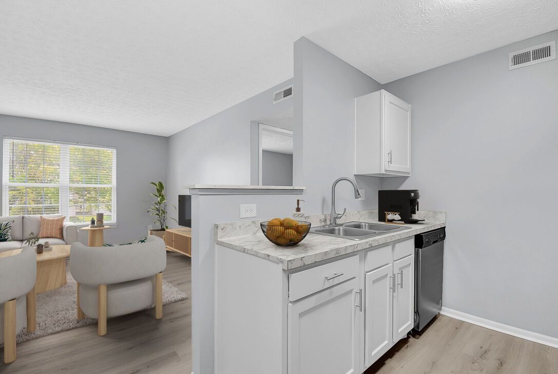 Bright modern kitchen and dining area with white cabinets, gray walls, and a table by the window.