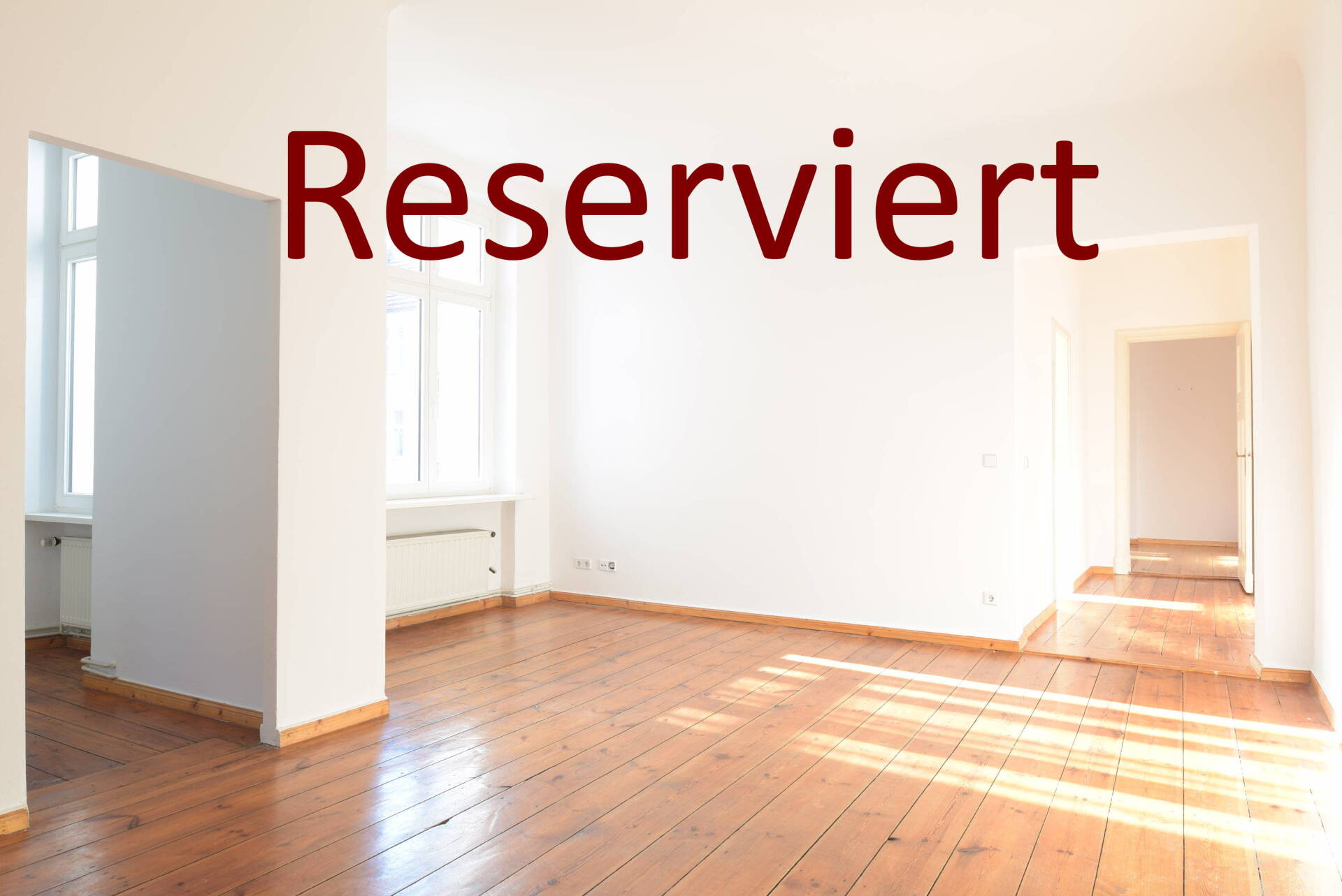Ein leerer Raum mit Holzboden und dem Wort „Reserviert“ darüber