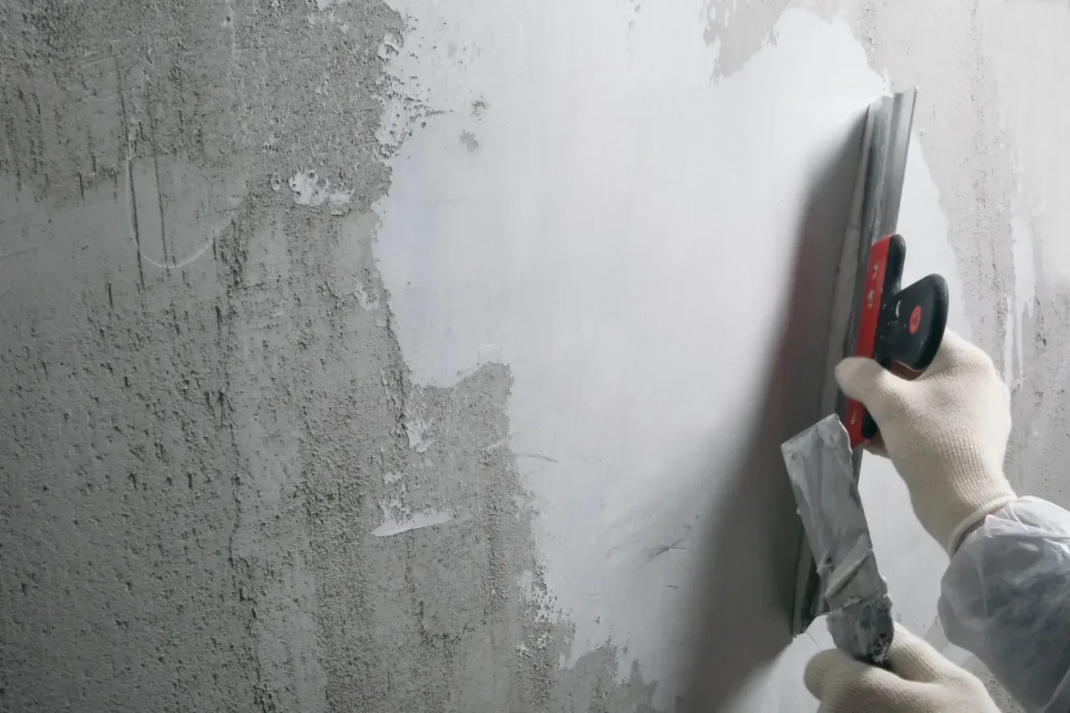 A man is working on a wall in a room.
