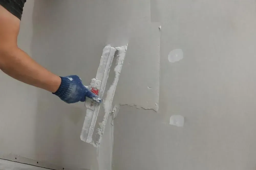 A man is working on a wall in a room.