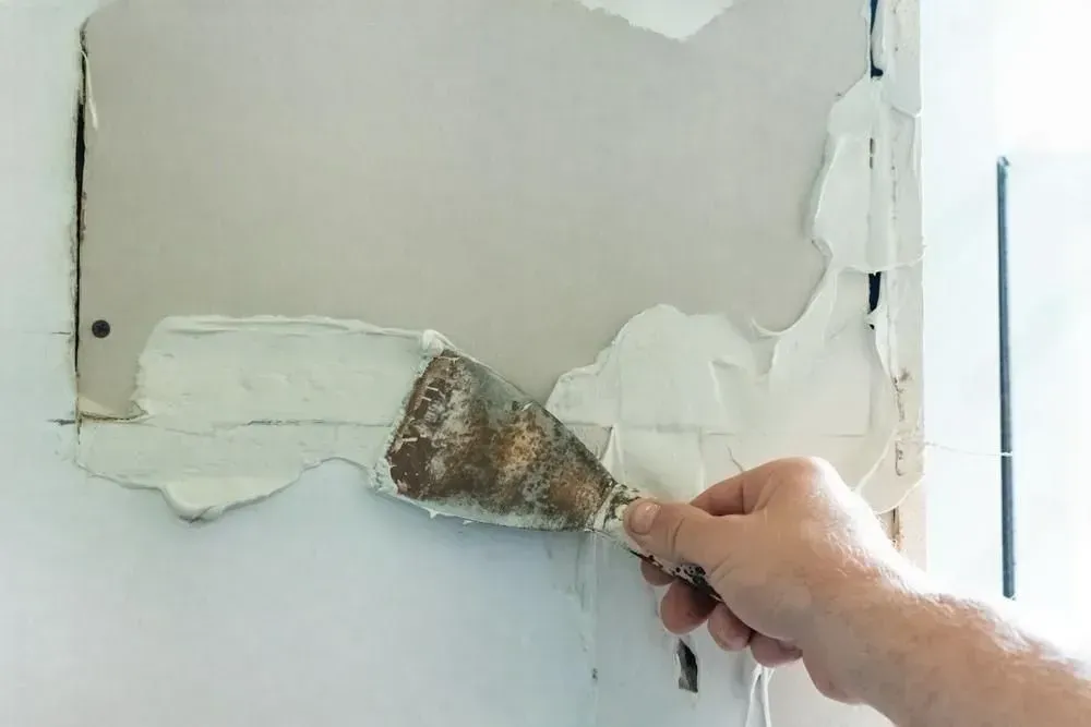 A man is working on a wall in a room.