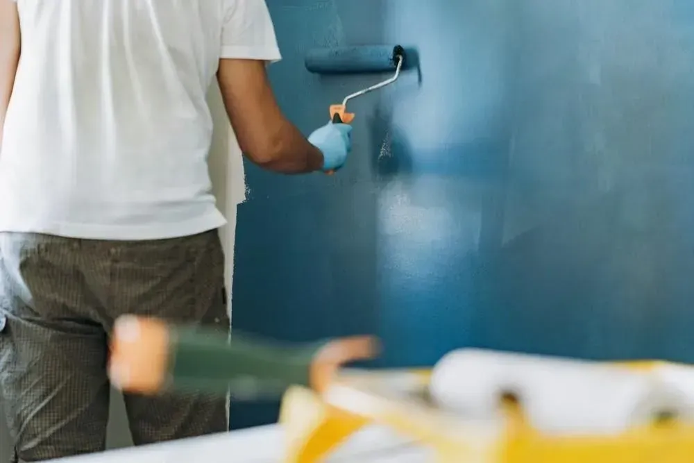A man is working on a wall in a room.