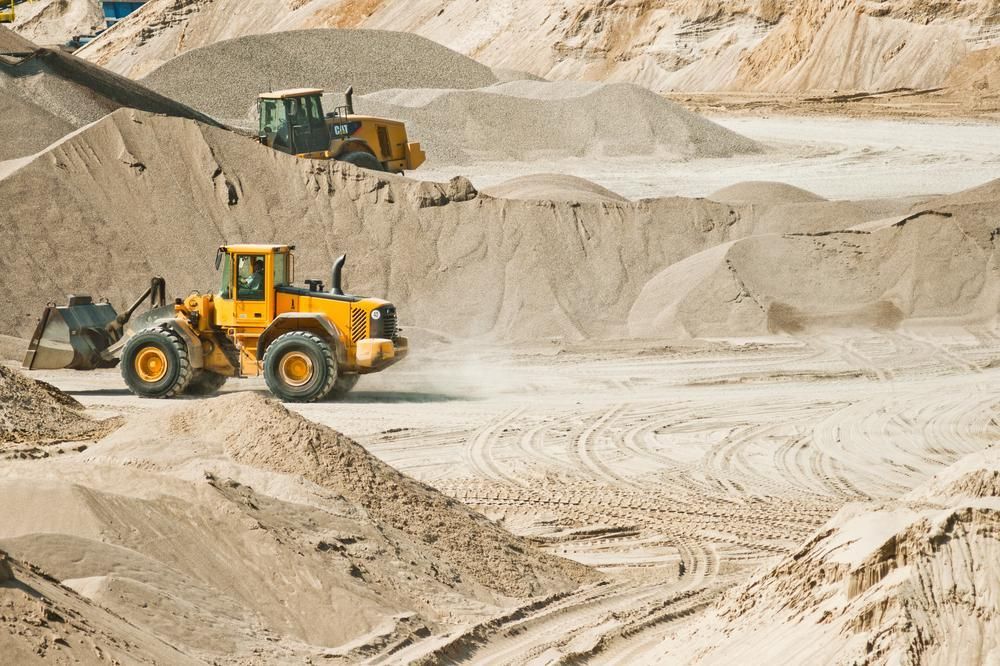 A Yellow Bulldozer is Driving Through a Pile of Sand — Chooks Sand And Gravel In Paget, QLD