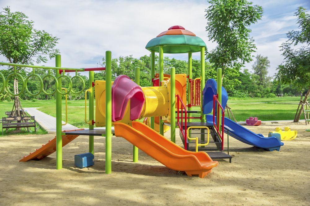 Colorful playground structure with slides, tunnels, and climbing bars on a sandy surface; trees in the background.— Chooks Sand And Gravel In Paget, QLD