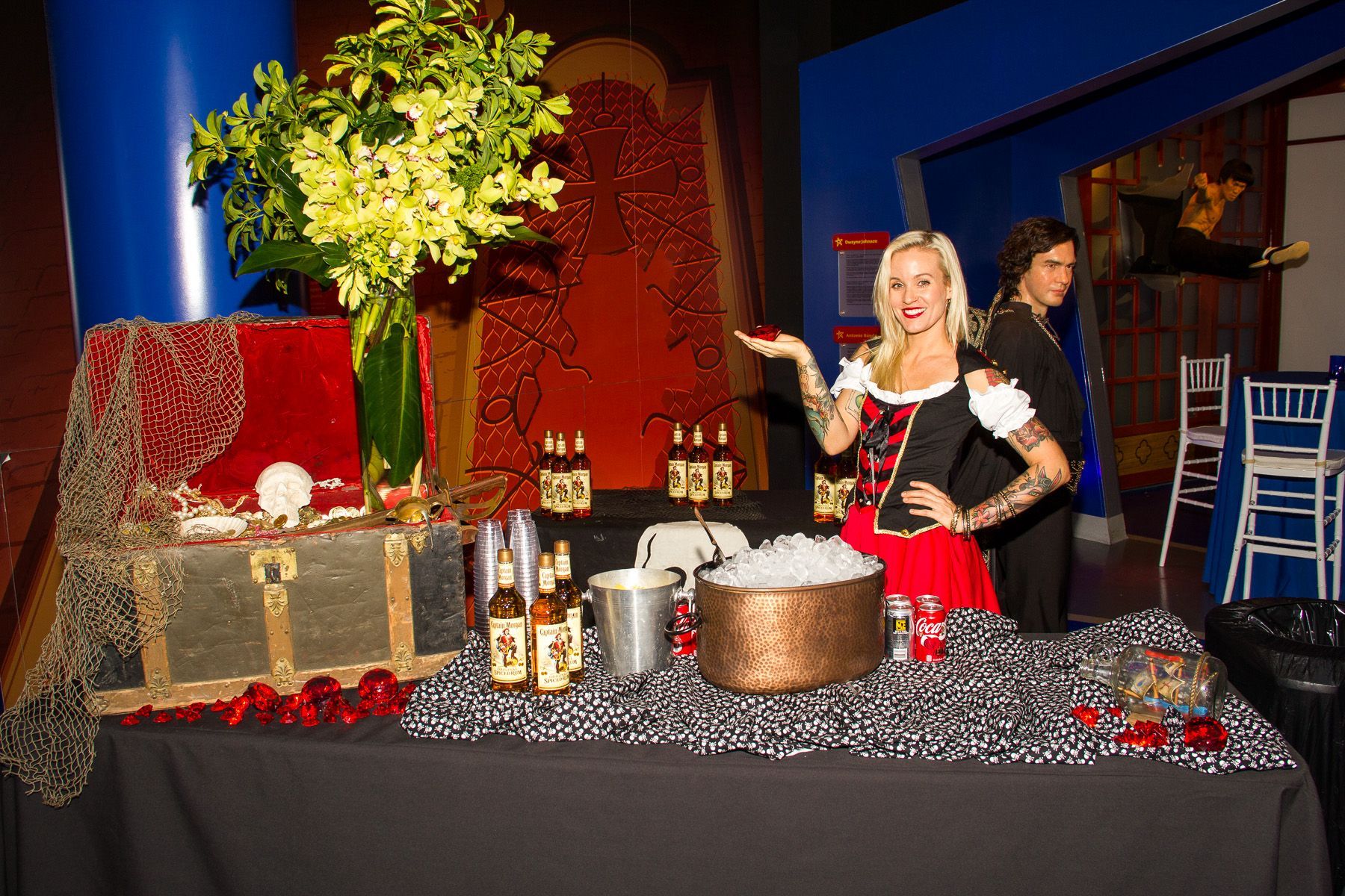 Holiday display with wrapped gifts, gold tree, and woman in red apron behind a table