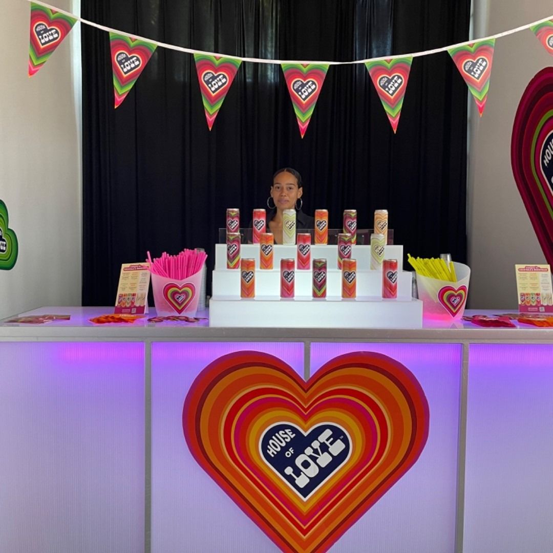 Decorated heart-themed display table with stacked boxes, bunting, and pink-purple lighting