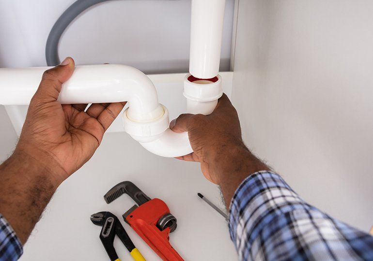 Plumber Fitting Sink Pipe In Kitchen — Sergeant Bluff, IA — Speedy Rooter Plumbing