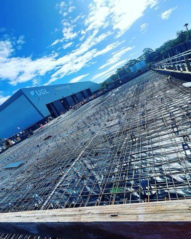 Construction site with rebar grid prepared for concrete, blue sky with clouds in the background.