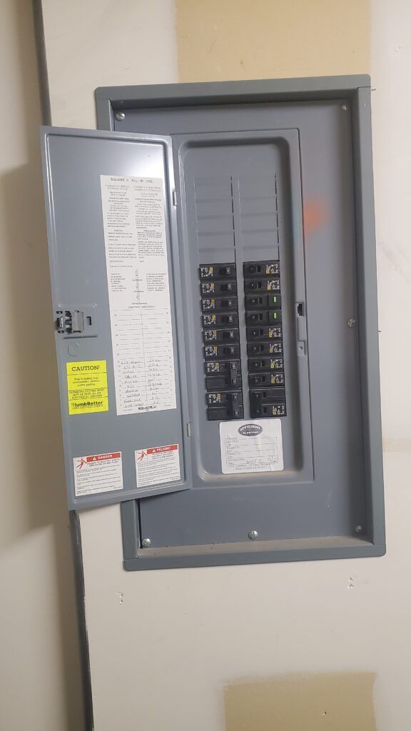 A electrical box is hanging on a wall with the door open.