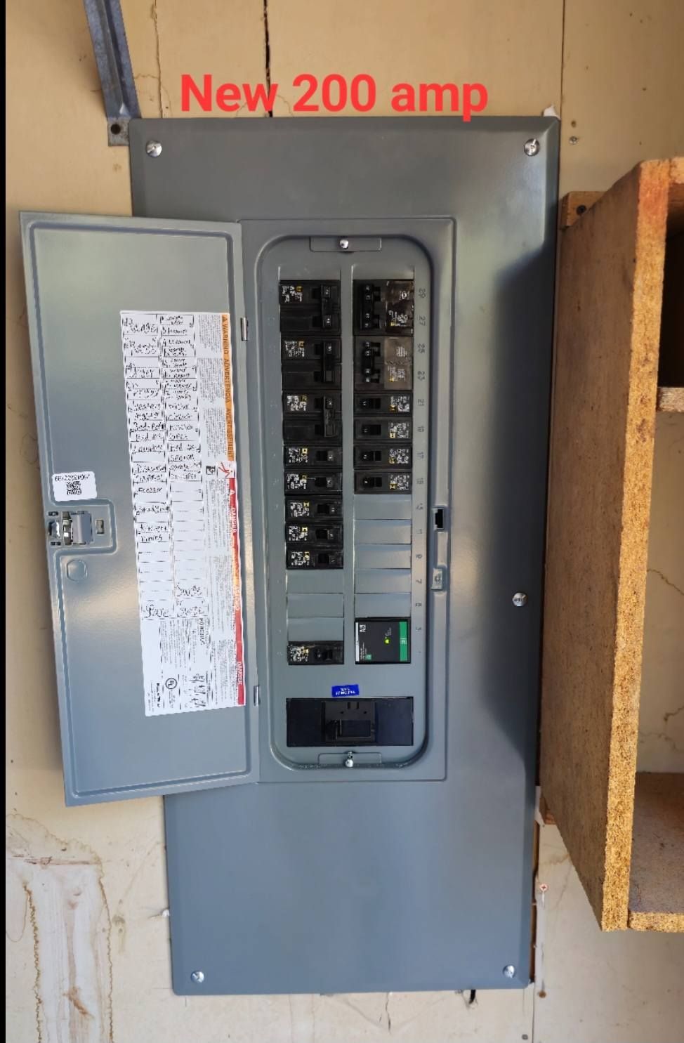 Open electrical breaker panel labeled “New 200 amp” on a gray wall.