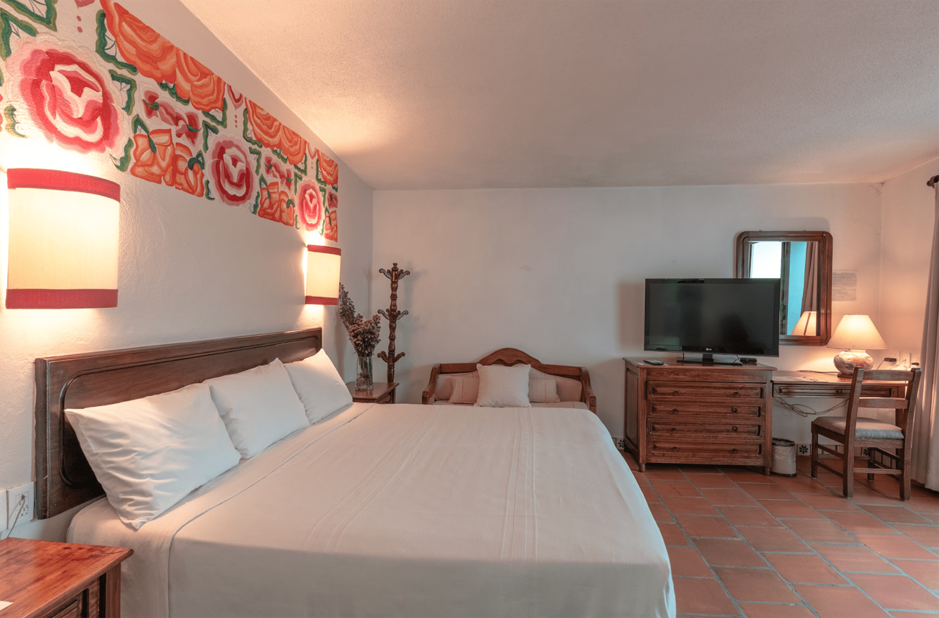 Una habitación de hotel con cama king size, cómoda, silla y televisión.
