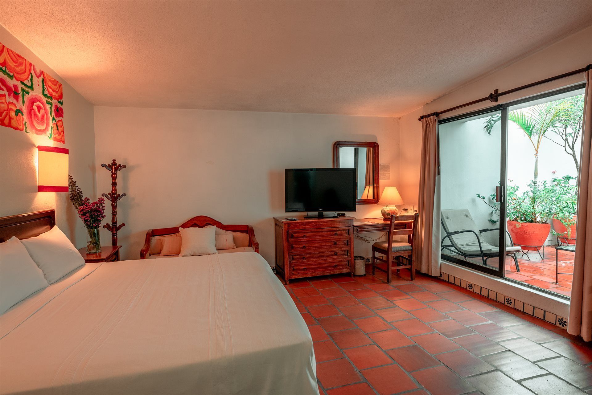 Una habitación de hotel con cama king size, televisión, escritorio y sillas.