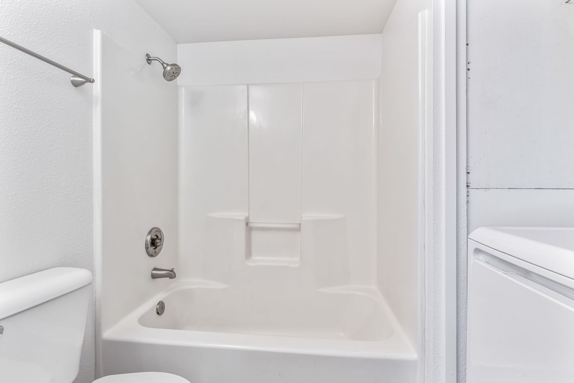 White bathroom with a shower, bathtub, toilet, and washing machine.