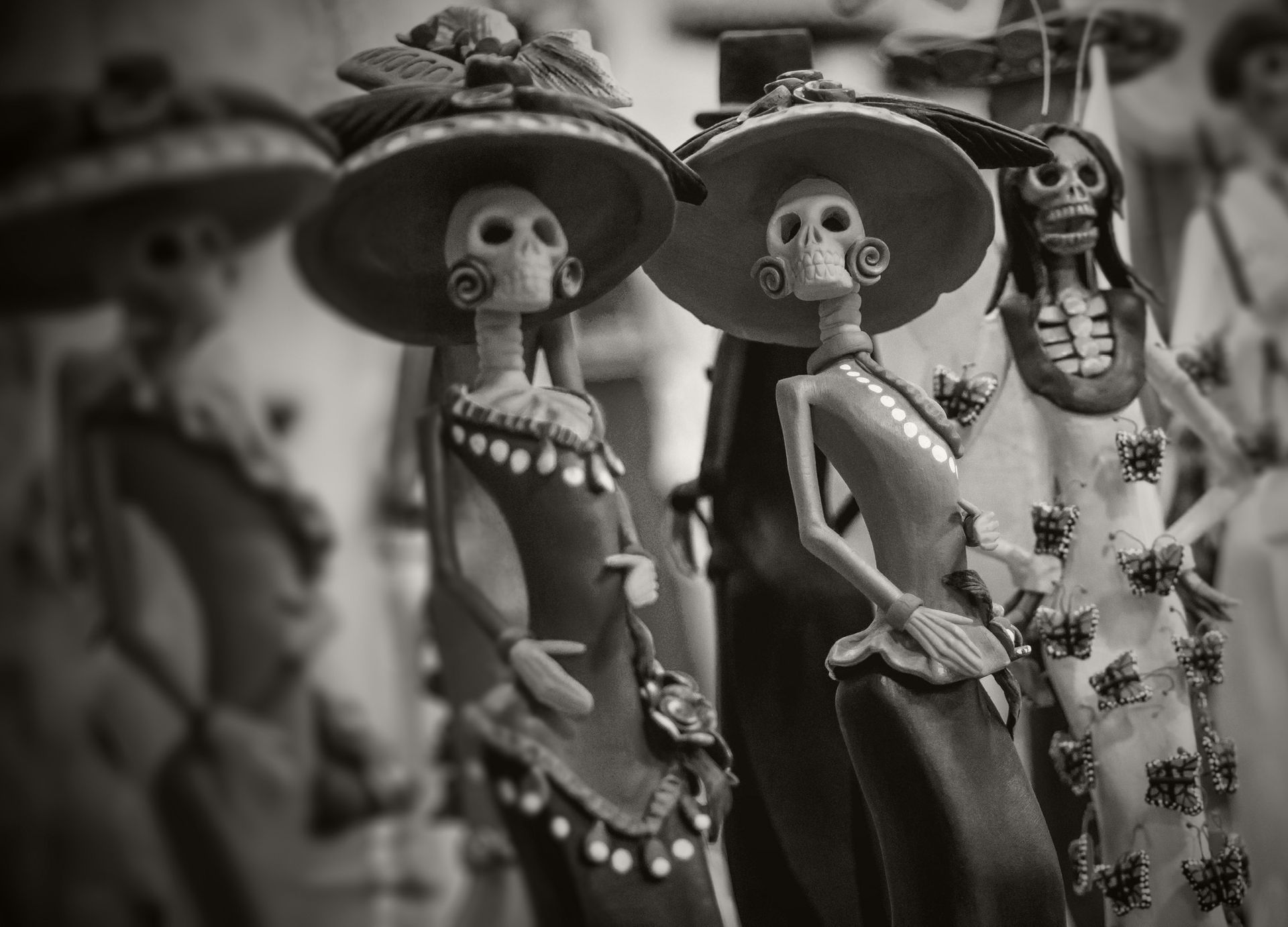 Figuras del Día de Muertos con caras de esqueleto, sombreros de ala ancha y vestidos ornamentados.