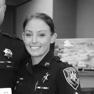 Smiling police officer in uniform standing beside another officer indoors