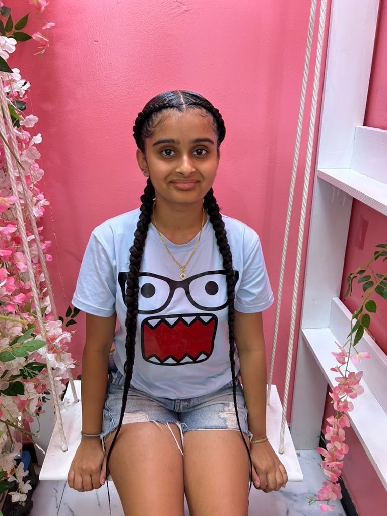 Person sitting on a bench in a pink alcove, wearing a white monster-face T-shirt and denim shorts.