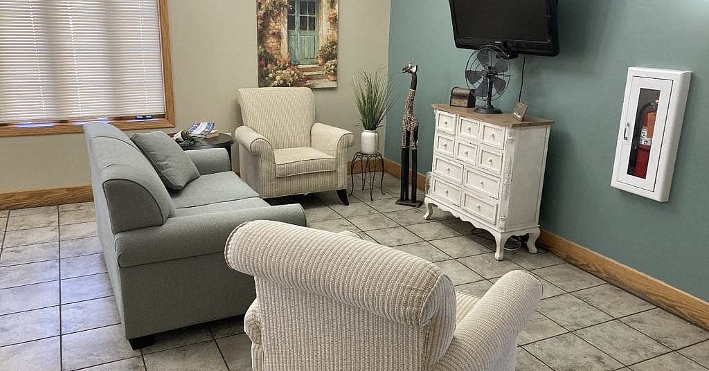 A living room with a couch , chairs , dresser and television.