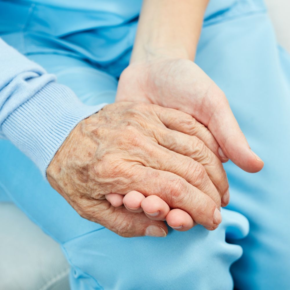 A woman is holding the hands of an older man