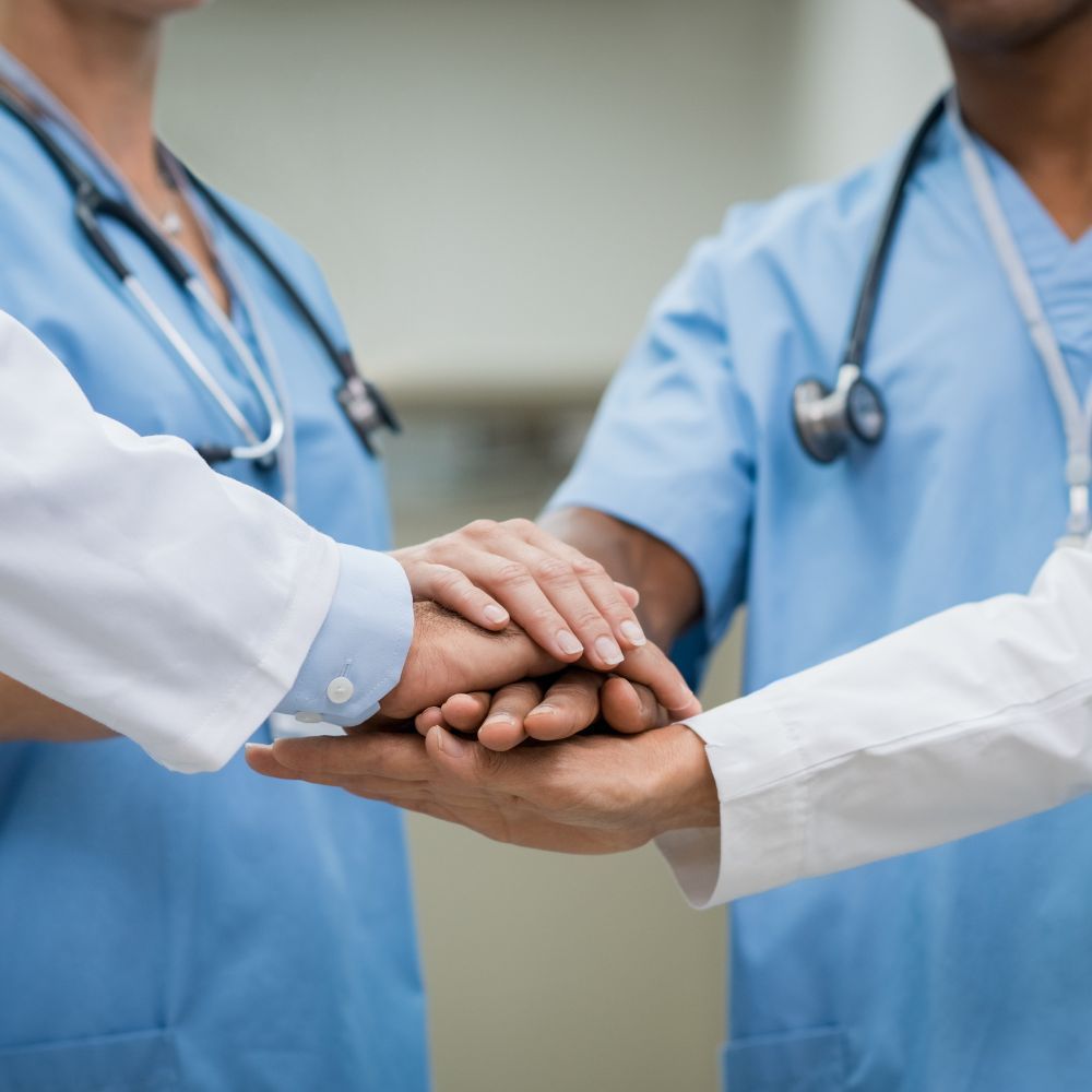 A group of doctors and nurses putting their hands together