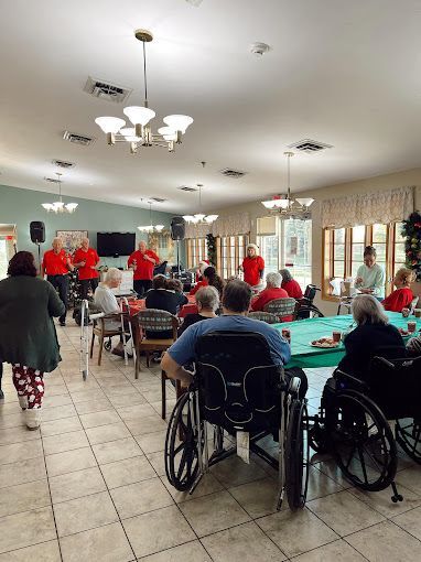 A group of people in wheelchairs are sitting at tables in a large room.