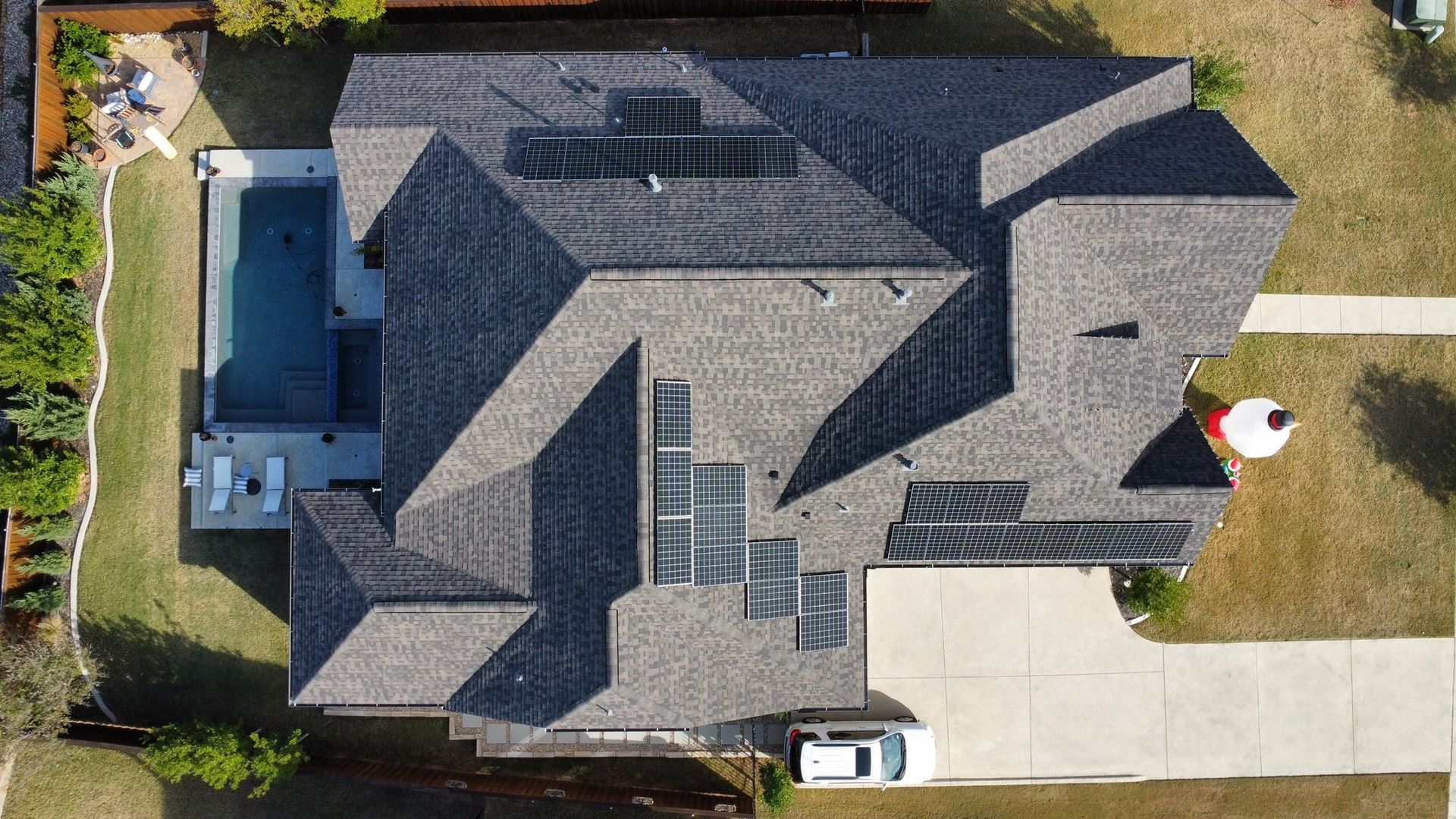 Overhead view of a house with gray shingles, a pool, and a white car in the driveway.