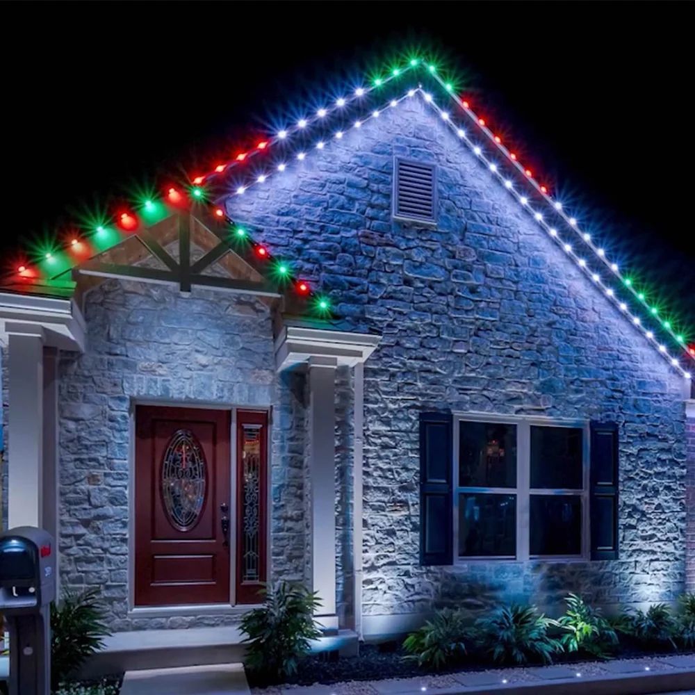 Stone house decorated with red, green, and white Christmas lights at night
