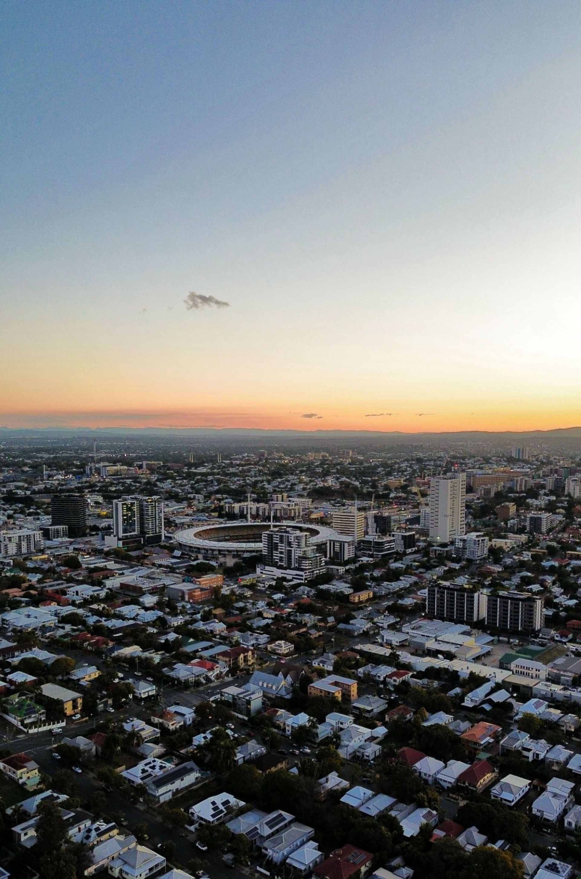 Aerial view of a snowy city at sunset with a pastel sky and distant skyline