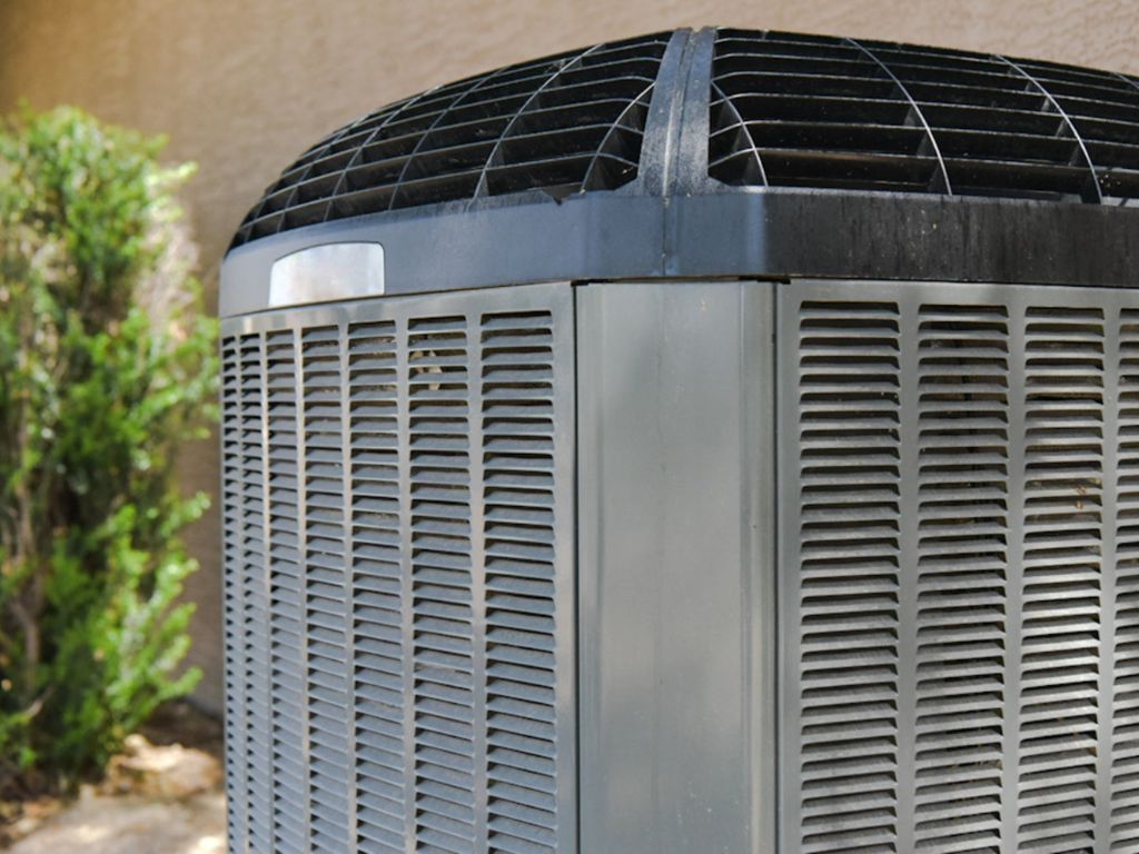 A large air conditioner is sitting on the side of a building.