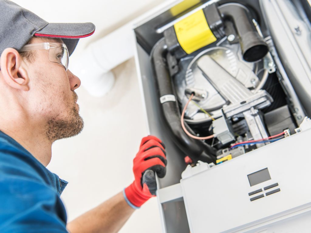 A man is working on a boiler with a wrench.