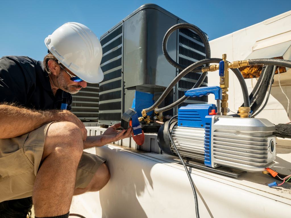 A man wearing a hard hat is working on an air conditioner.