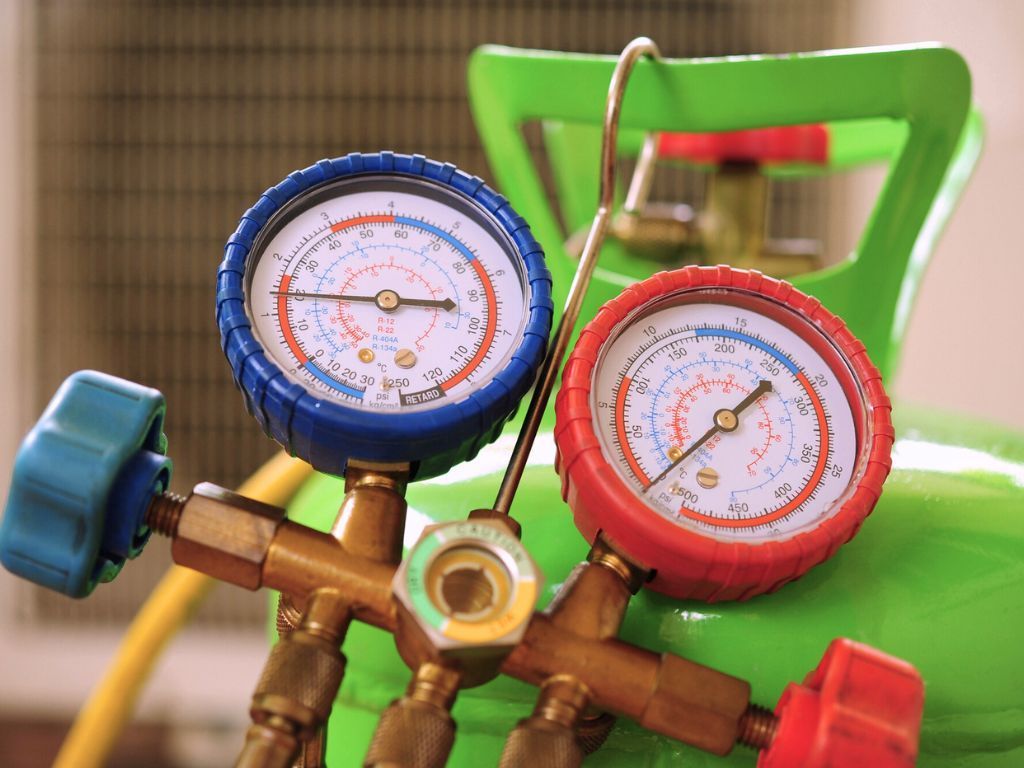 Two pressure gauges are sitting on top of a green tank. Two pressure gauges are sitting on top of a green tank.
