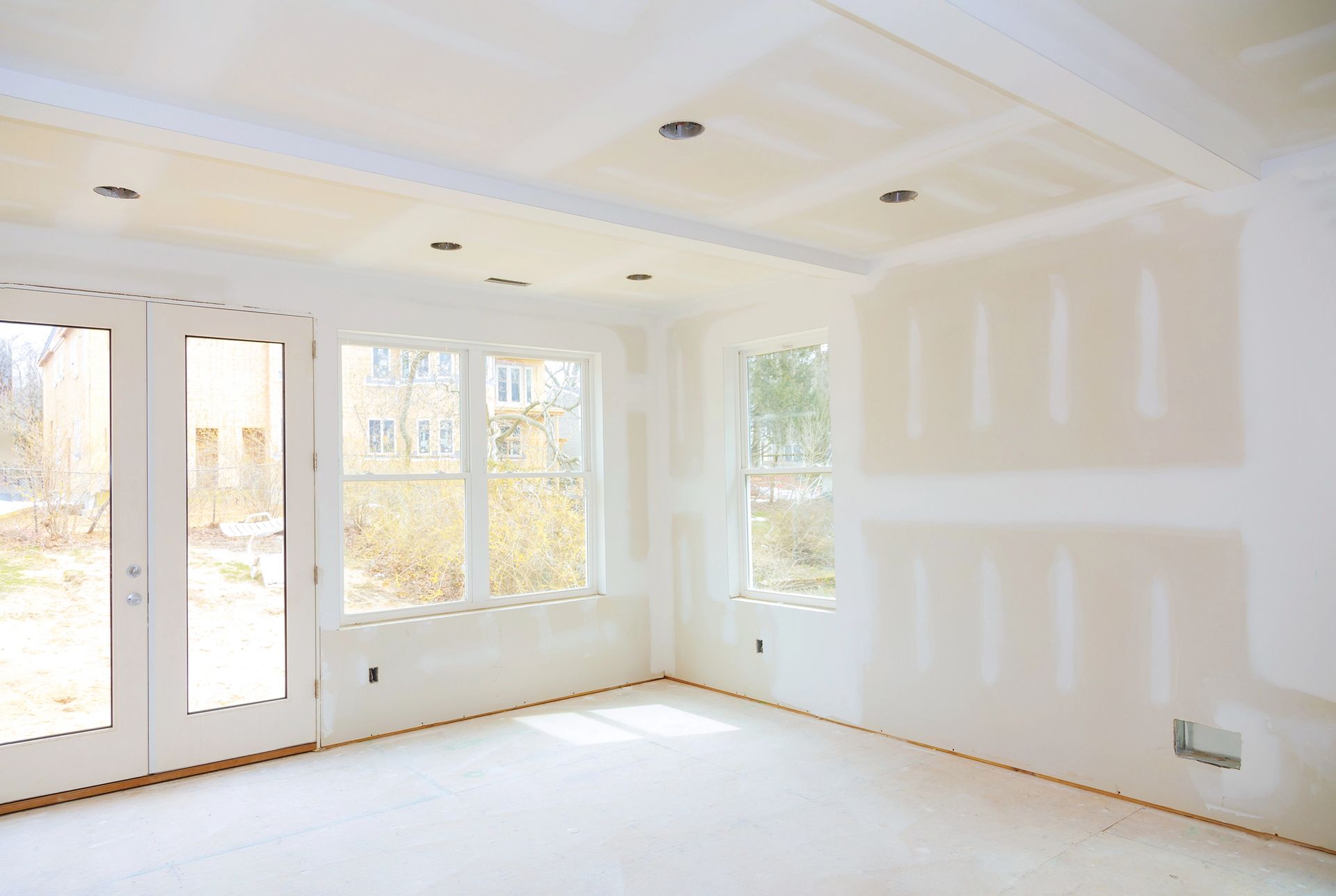 Stanza interna in costruzione con cartongesso su pareti e soffitto, finestre e porte.