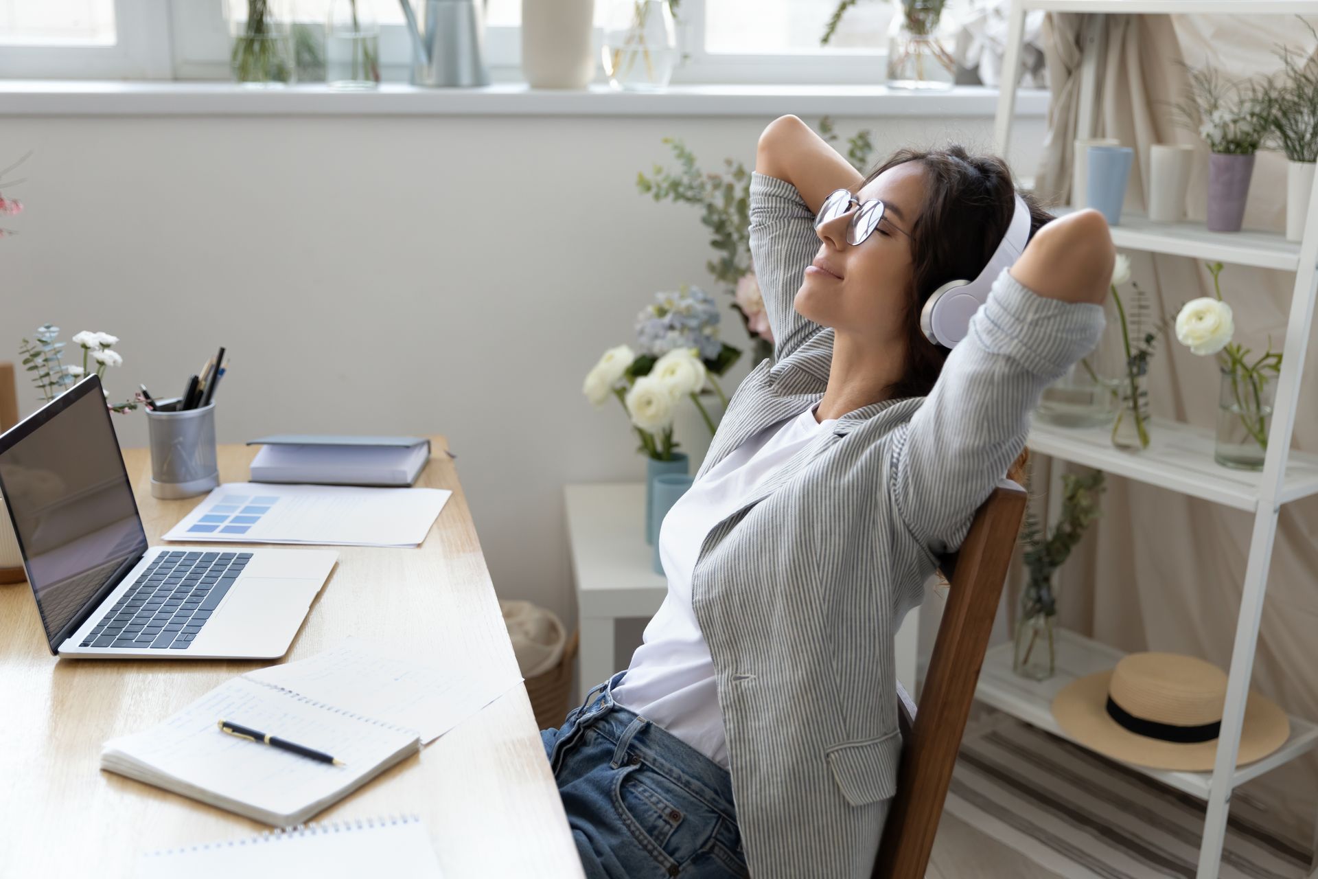 Person relaxing at a desk with laptop, leaning back in a bright home office