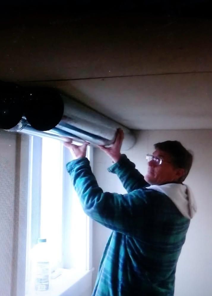 A person is holding a gauge in front of an air conditioner.