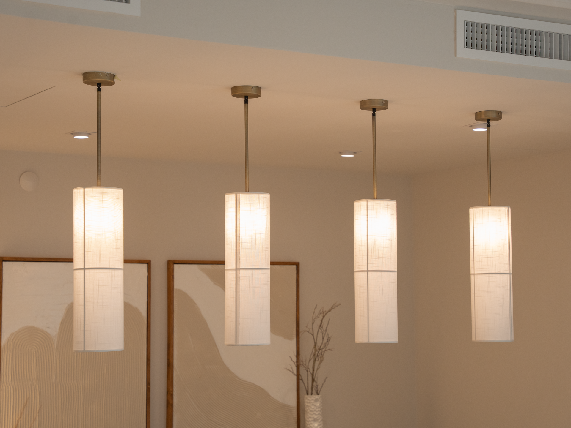 Four modern hanging pendant lights illuminating a minimalist interior