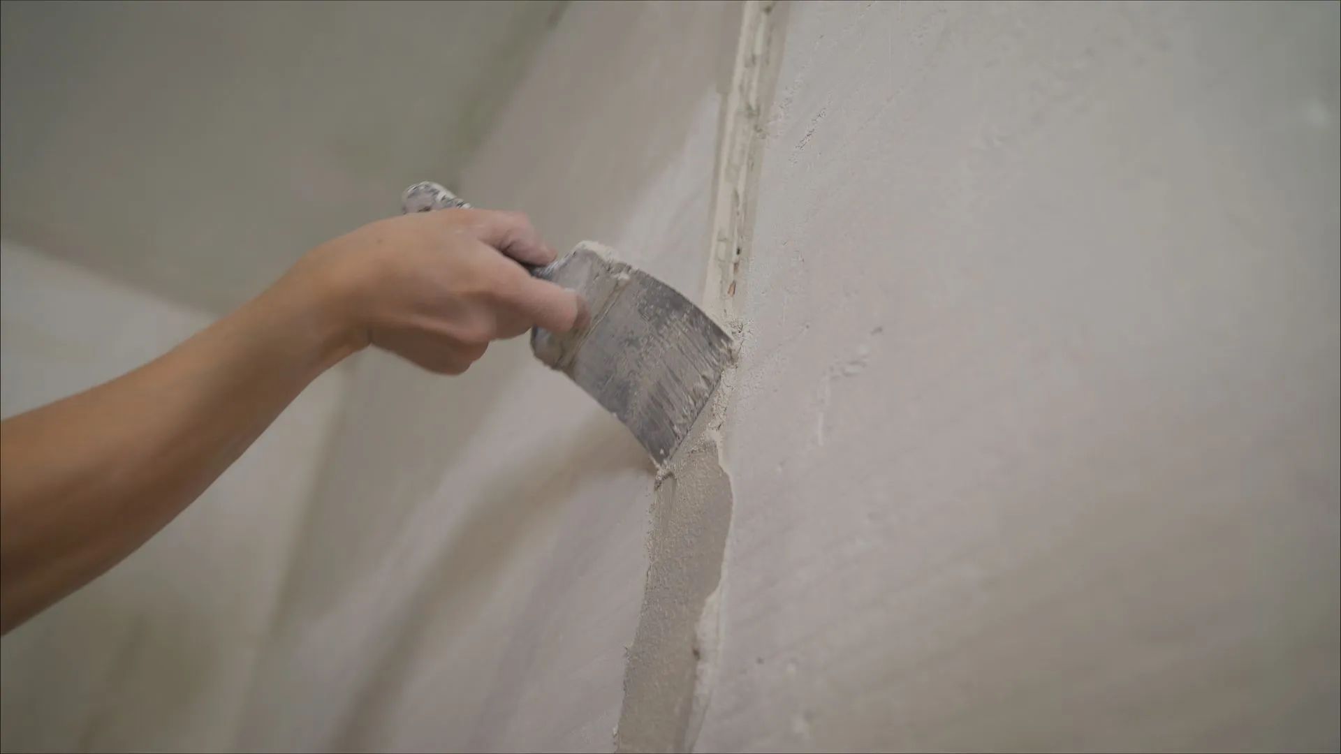 Hand trowel applying plaster to a wall seam during repair work