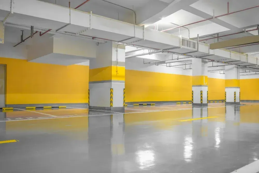 Empty indoor parking garage with yellow walls and polished concrete floor