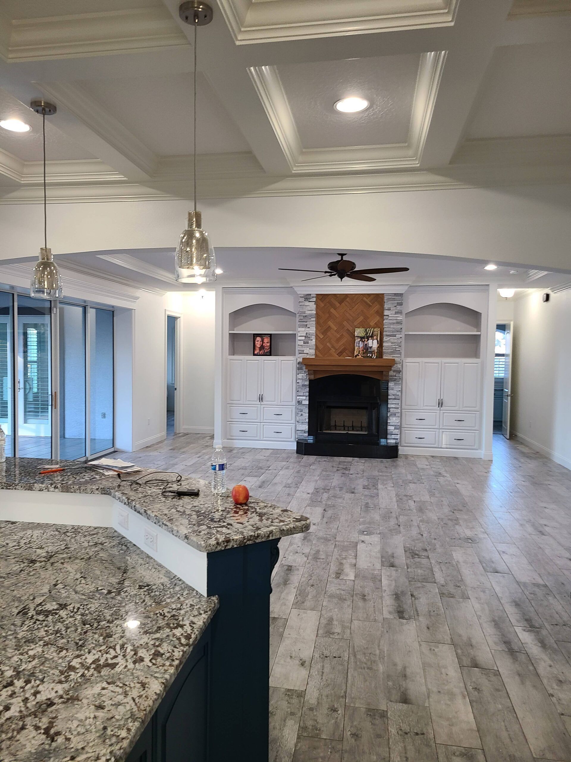 Spacious open kitchen and living room with granite island, hardwood floors, fireplace, and tray ceiling.