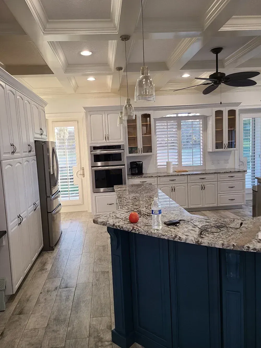 Bright kitchen with granite island, white cabinets, vaulted ceiling, and dark blue island base.