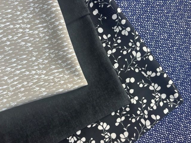 Stacked fabric swatches in gray, black, floral navy, and blue patterns